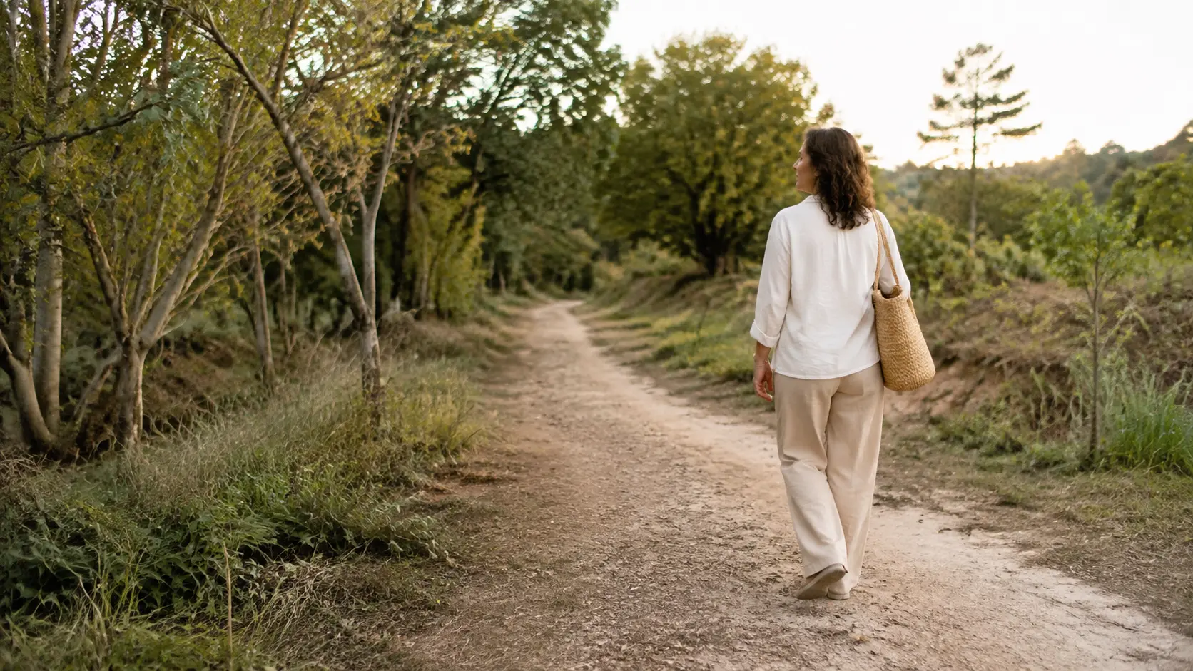 Mulher caminhando por um caminho cercado de vegetação.